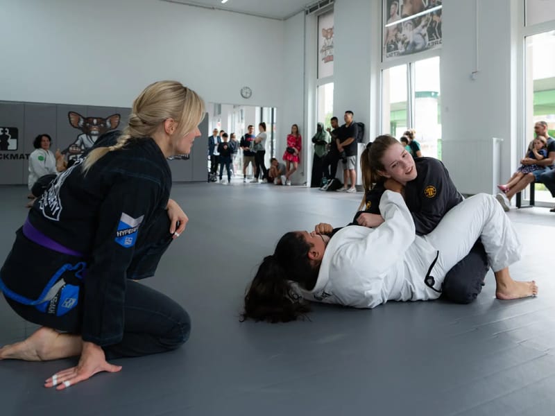 Coach begleitet zwei Teilnehmerinnen beim Techniktraining in der hellen Halle in der Seestadt